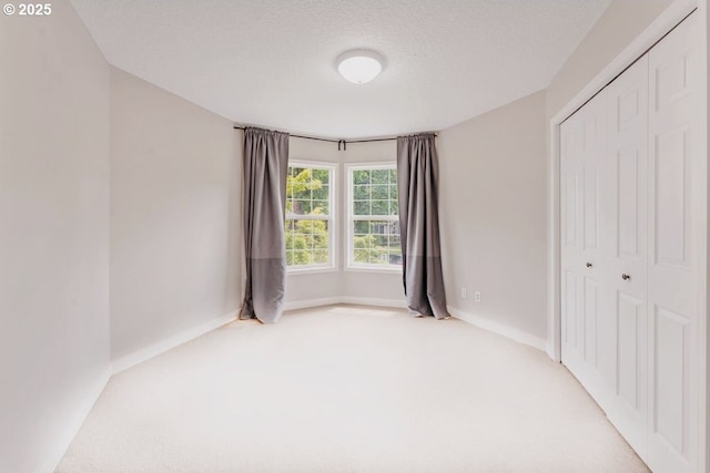 unfurnished bedroom with carpet floors, a closet, baseboards, and a textured ceiling