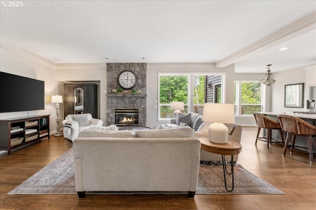 living room featuring a fireplace, dark wood-type flooring, baseboards, crown molding, and a textured ceiling