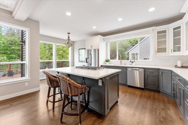 kitchen with appliances with stainless steel finishes, gray cabinets, a center island, recessed lighting, and light countertops