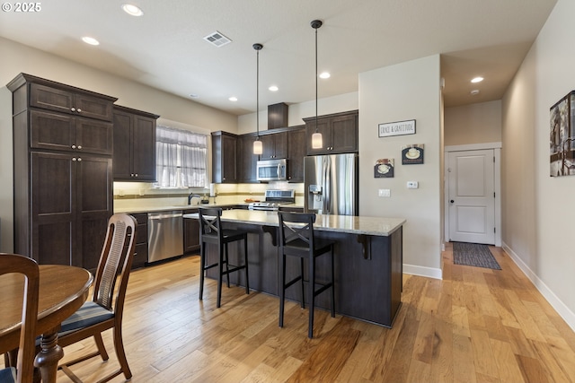 16033 SW 2nd St, Sherwood, OR 97140 - kitchen featuring stainless steel appliances, dark brown cabinets, light wood finished floors, a kitchen breakfast bar, and a center island