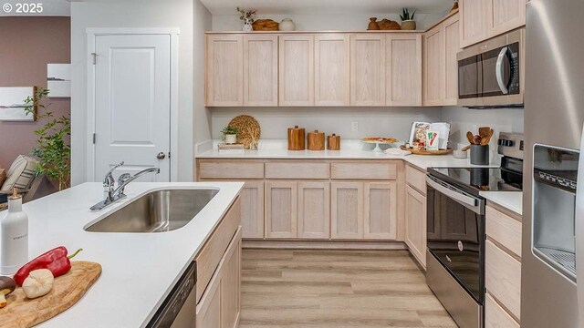 kitchen featuring dishwasher, light brown cabinets, sink, light wood-type flooring, and a kitchen island