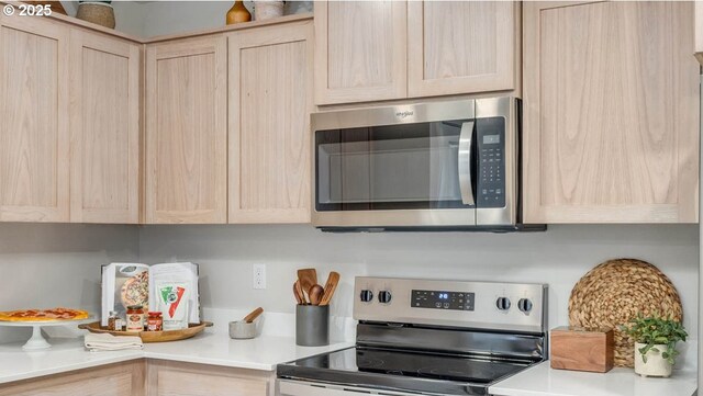 kitchen with appliances with stainless steel finishes, light brown cabinets, an AC wall unit, and a kitchen island with sink