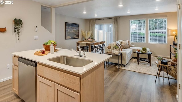 kitchen featuring sink, light hardwood / wood-style floors, an island with sink, stainless steel dishwasher, and light brown cabinets