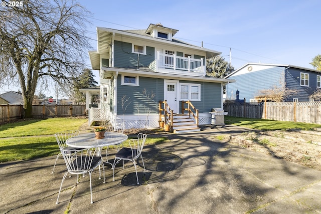 rear view of property with a patio, a balcony, and a lawn