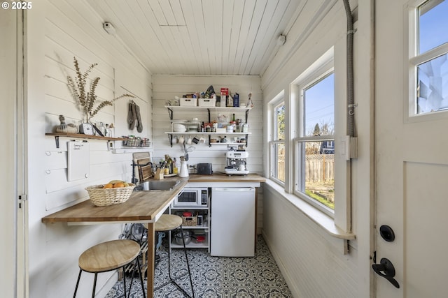 interior space featuring white microwave, refrigerator, butcher block counters, sink, and wood ceiling