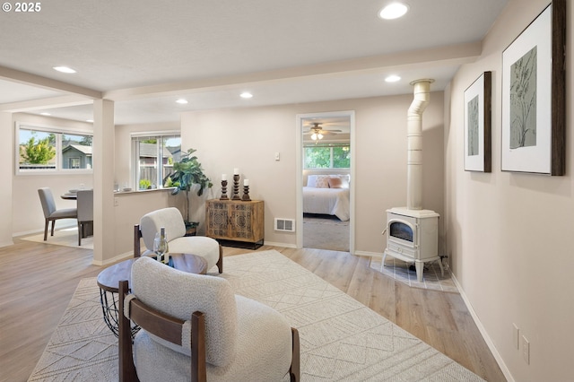 living area featuring healthy amount of natural light, a wood stove, wood finished floors, recessed lighting, and baseboards