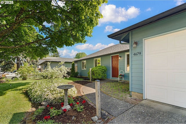 doorway to property with a lawn and an attached garage