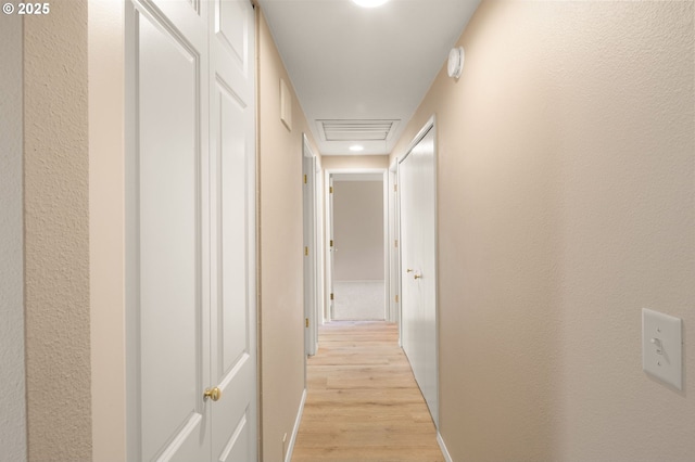 corridor with light wood-style flooring and baseboards
