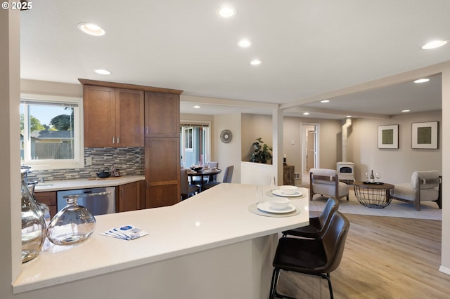 kitchen featuring dishwasher, light countertops, recessed lighting, light wood finished floors, and decorative backsplash