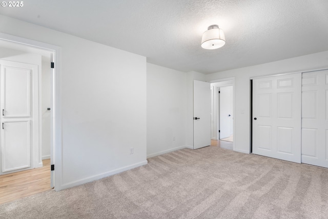 unfurnished bedroom featuring light colored carpet, a closet, and a textured ceiling