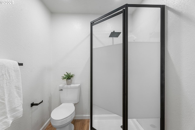 bathroom with toilet, hardwood / wood-style floors, and a shower with shower door