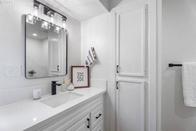 bathroom with a textured wall and vanity