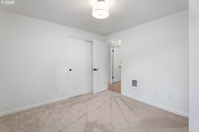 spare room with a textured ceiling, carpet, visible vents, and baseboards