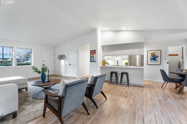 living room with light wood finished floors, baseboards, and high vaulted ceiling