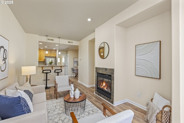 living area with light wood-type flooring, baseboards, visible vents, and a tile fireplace