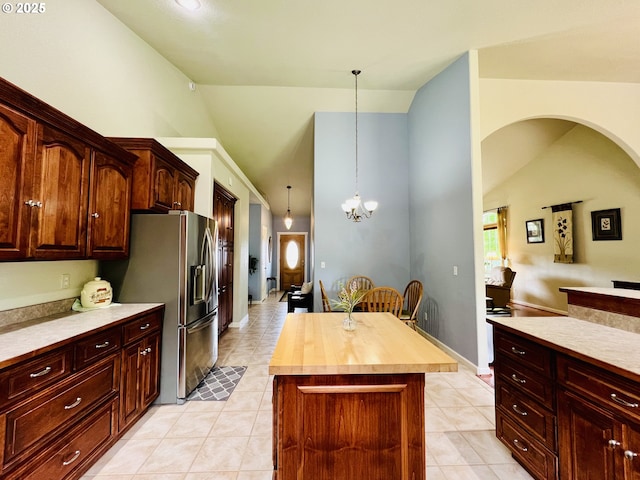 2295 Chi Chi Ln, Sutherlin, OR 97479 - kitchen featuring light tile patterned floors, stainless steel refrigerator with ice dispenser, a center island, high vaulted ceiling, and decorative light fixtures