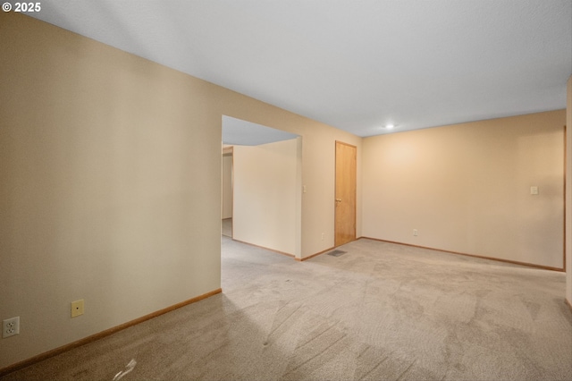 unfurnished room featuring baseboards, visible vents, and light colored carpet