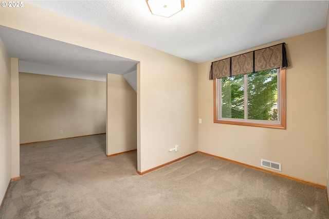 carpeted empty room with a textured ceiling, baseboards, and visible vents