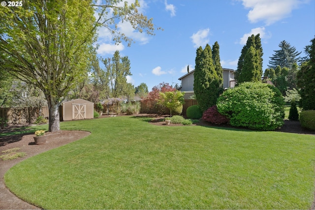 view of yard featuring a fenced backyard, a shed, and an outbuilding