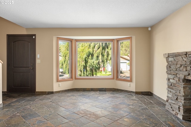 unfurnished living room featuring baseboards, plenty of natural light, and stone tile flooring