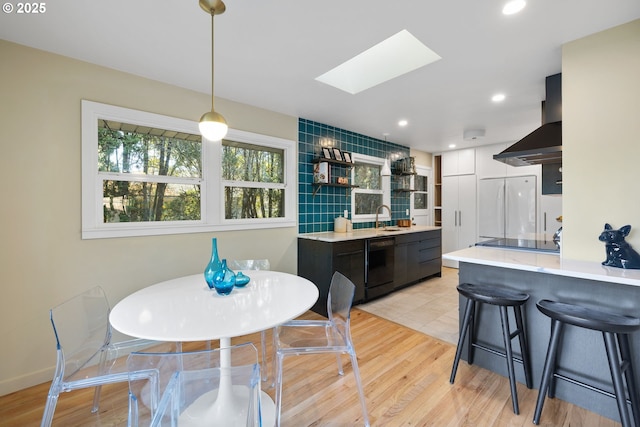 dining space with sink, light hardwood / wood-style floors, and a skylight