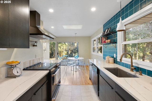 kitchen with sink, light stone counters, decorative light fixtures, electric range, and exhaust hood