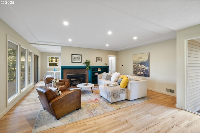 living room with a brick fireplace and light hardwood / wood-style flooring