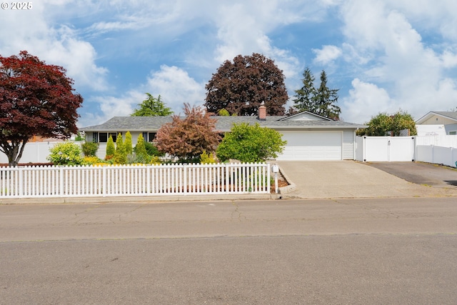 ranch-style home featuring a garage, a gate, a chimney, concrete driveway, and fence private yard