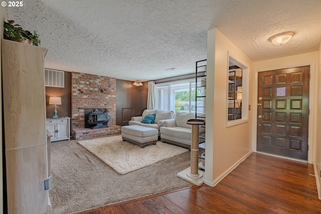 living room featuring baseboards, a wood stove, a textured ceiling, and wood finished floors