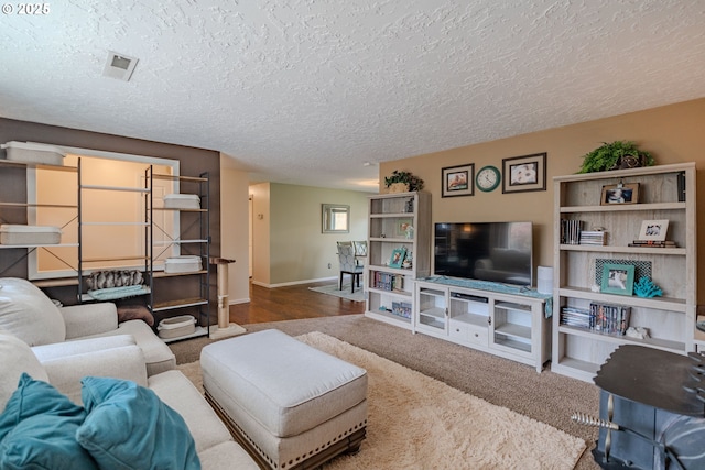 living area with baseboards, a textured ceiling, and visible vents