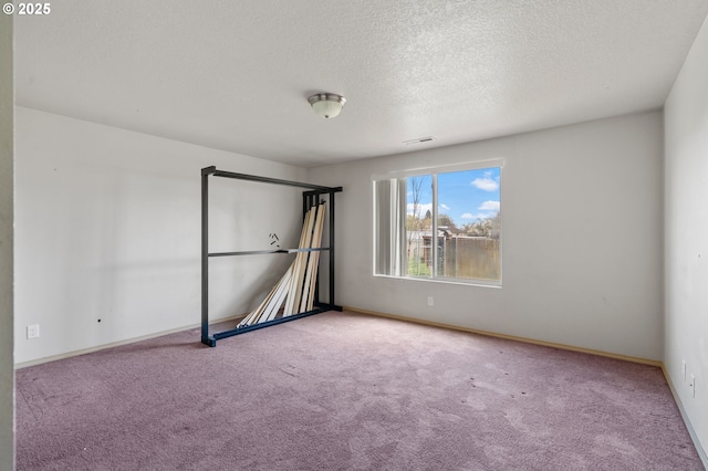 interior space featuring visible vents, a textured ceiling, baseboards, and carpet floors