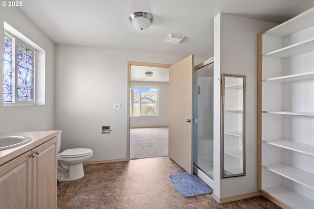 bathroom with toilet, a stall shower, vanity, and baseboards