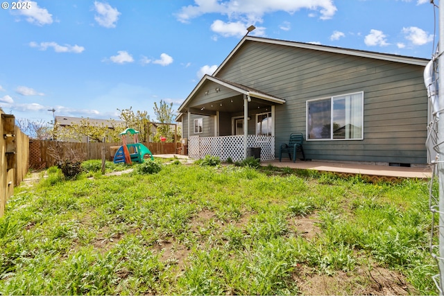 rear view of property featuring a patio area, a fenced backyard, and a playground