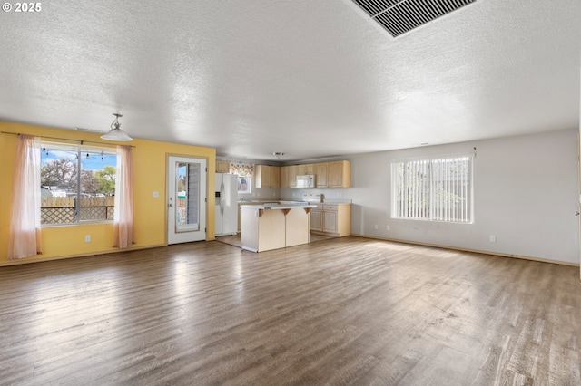 unfurnished living room with visible vents, baseboards, light wood-type flooring, and a textured ceiling