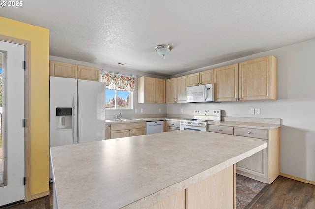 kitchen featuring a sink, light countertops, white appliances, and light brown cabinetry