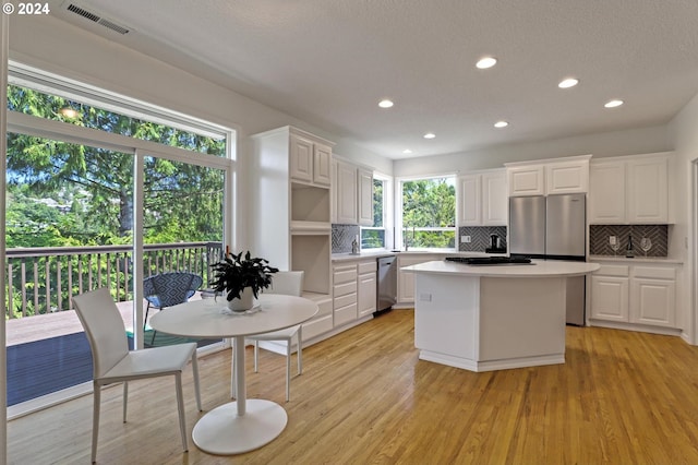 kitchen featuring backsplash, white cabinets, a center island, stainless steel dishwasher, and light hardwood / wood-style floors