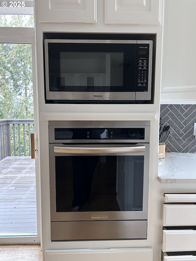 details featuring stainless steel appliances, white cabinetry, and decorative backsplash