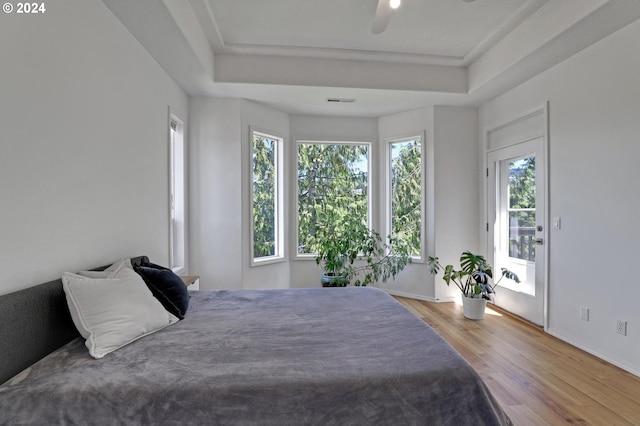 bedroom featuring a raised ceiling, hardwood / wood-style floors, access to exterior, and ceiling fan