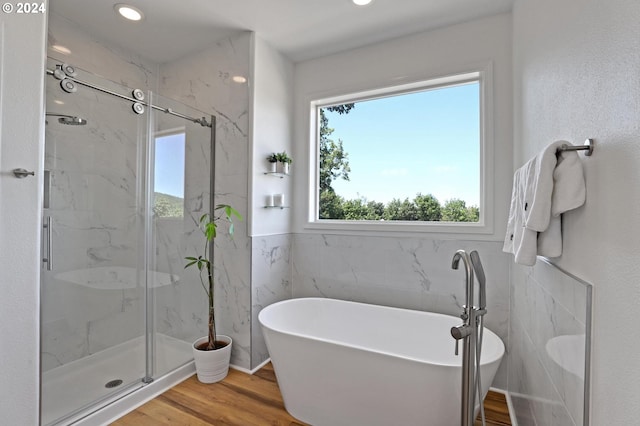 bathroom with independent shower and bath, wood-type flooring, and tile walls