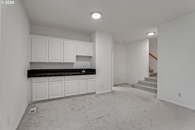 kitchen featuring white cabinetry, sink, and light colored carpet