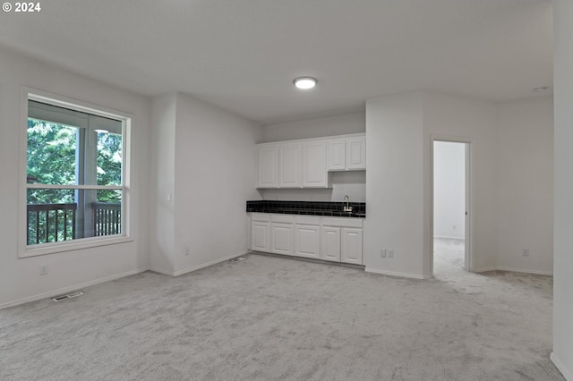 unfurnished living room with light colored carpet and sink