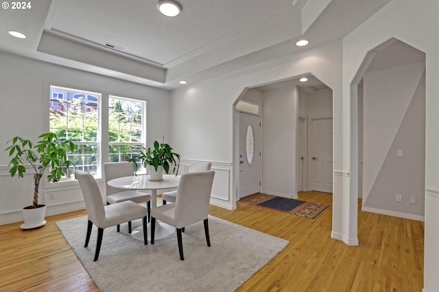 dining room featuring light wood-type flooring and a tray ceiling