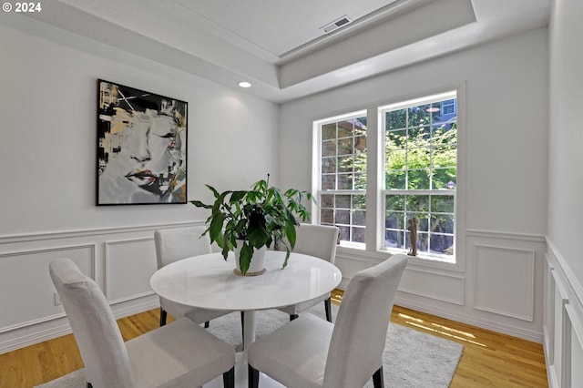 dining room featuring a raised ceiling and light wood-type flooring