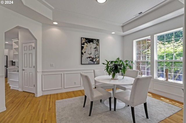 dining area featuring a tray ceiling and light hardwood / wood-style flooring