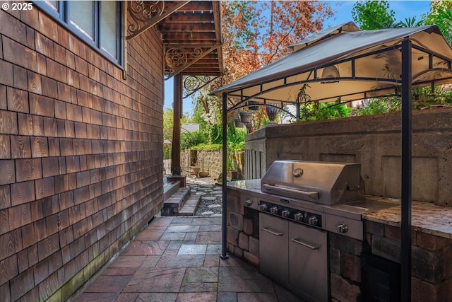 view of patio with area for grilling, a gazebo, and fence