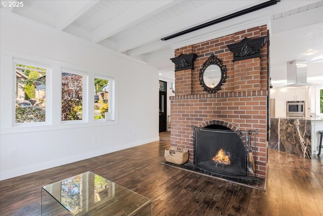 unfurnished living room featuring baseboards, beamed ceiling, a brick fireplace, and hardwood / wood-style flooring