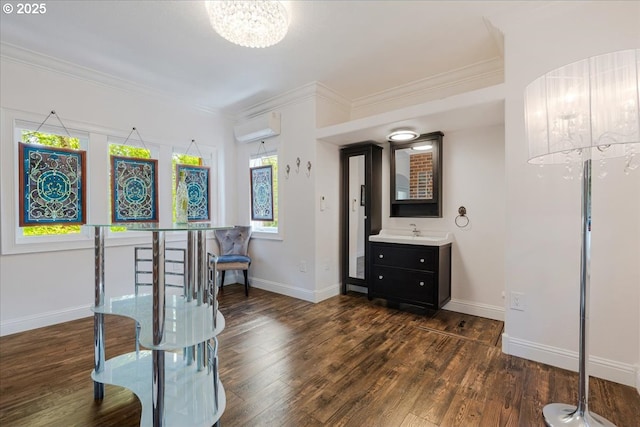 sitting room with crown molding, dark wood-style flooring, a wall unit AC, and a chandelier