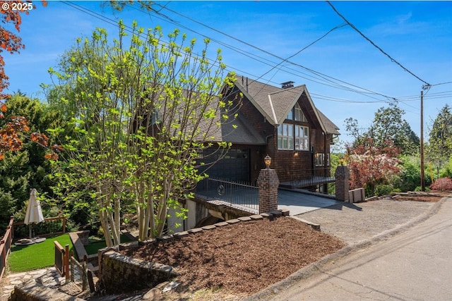 view of side of home featuring an attached garage, driveway, and roof with shingles