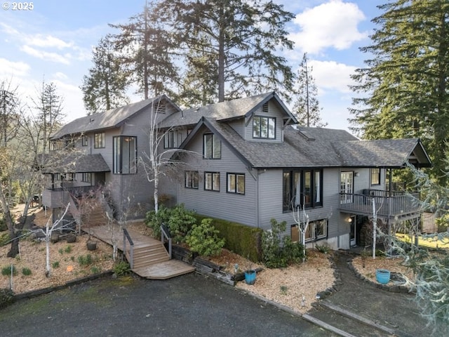 view of front of home with roof with shingles and stairway