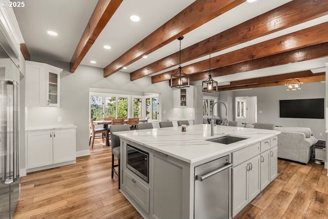 kitchen featuring stainless steel appliances, open floor plan, a sink, and light wood finished floors